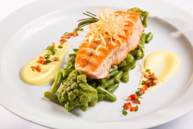 Beyaz tabakta yeşil fasulyeli somon bifteği