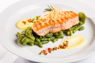 Beyaz tabakta yeşil fasulyeli somon bifteği