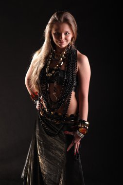 Siyah arka planda boncuk ve bilezikler takan güzel bir genç kız.