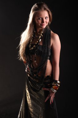 Siyah arka planda boncuk ve bilezikler takan güzel bir genç kız.