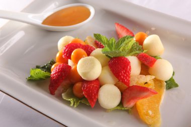 Tabakta tatlı soslu meyve ve meyve salatası.