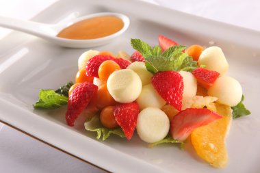 Tabakta tatlı soslu meyve ve meyve salatası.