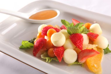 Tabakta tatlı soslu meyve ve meyve salatası.