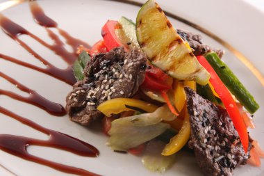 Sebzeli biftek ve tabakta susam sosu.