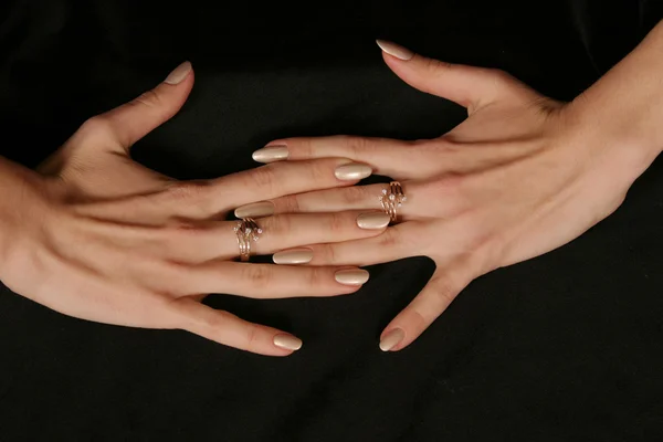 female hand holding fingers diamond ring on black background