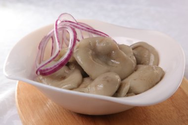 Beyaz tabakta soğanlı tuzlanmış mantar.