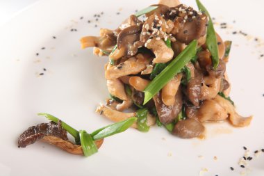 Tabağında et olan sıcak mantar salatası.