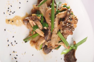 Tabağında et olan sıcak mantar salatası.