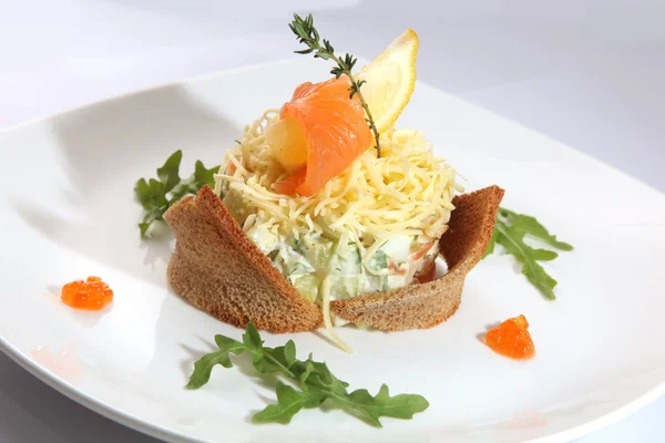 Russian salad with smoked salmon and toast on plate