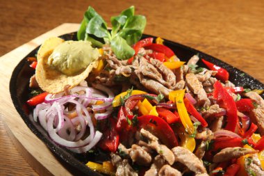 ahşap masa üzerinde tavada sığır eti fajita