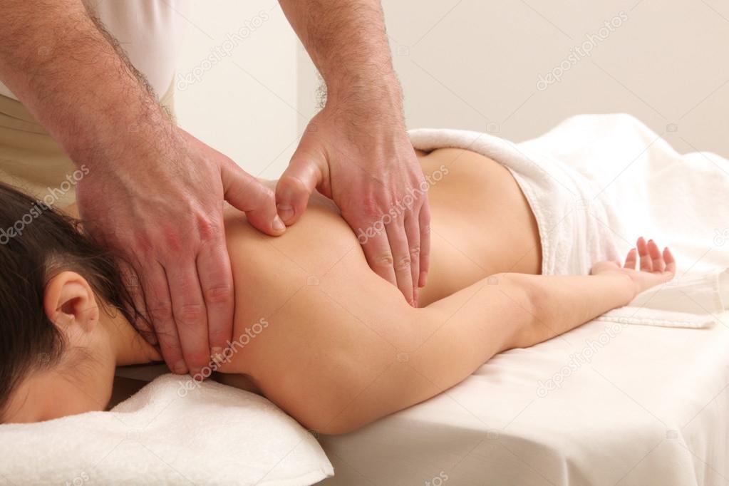 Masseur doing massage on woman body in the spa salon.