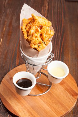 Tahta masadaki kese kağıdında tavuk parçaları.