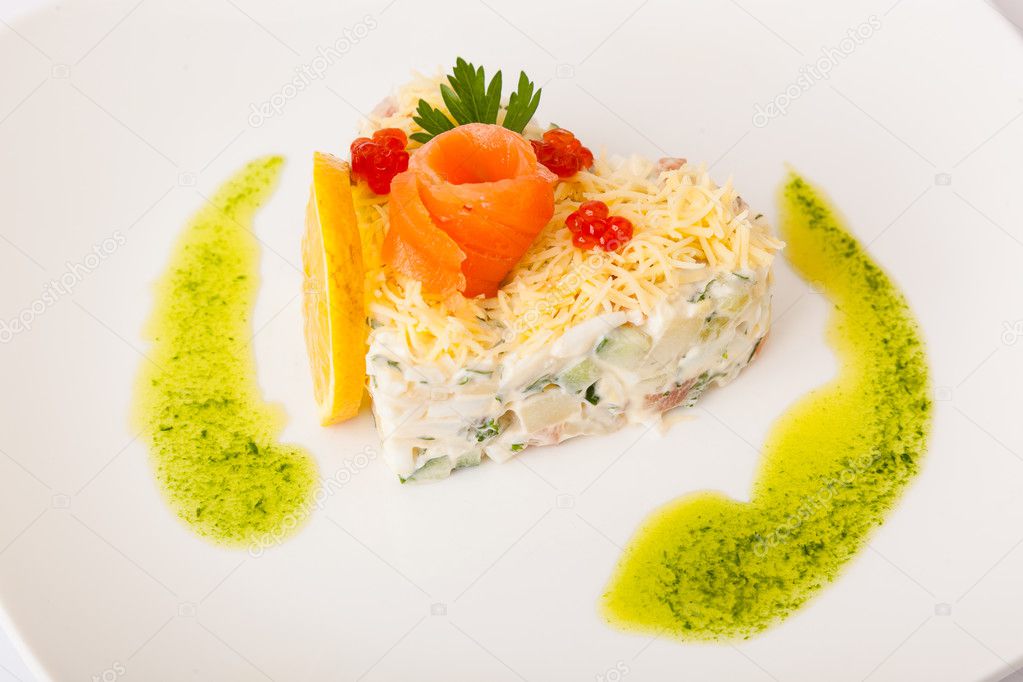 Salad with red fish and caviar on white plate