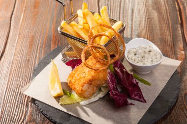 Tahta masada patates kızartması ve tartar soslu balık.