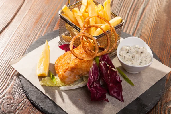 fish with fries and tartar sauce on wooden table