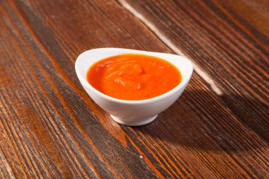 Ahşap bir masada kaseli kırmızı domates sosu.