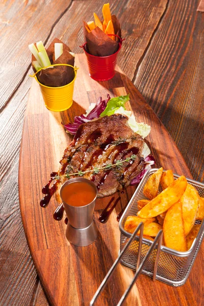 pork steak with French fries on a wooden cutting board with sauce
