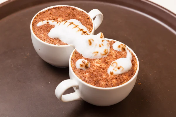Coffee with foam in the form of a cat and a mouse on brown table