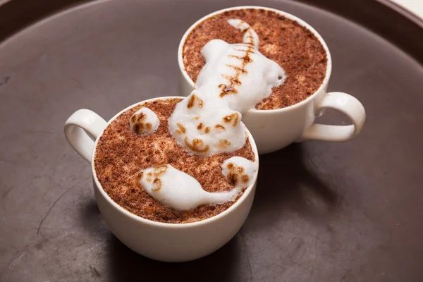 Coffee with foam in the form of a cat and a mouse on brown table