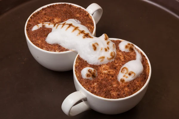 Coffee with foam in the form of a cat and a mouse on brown table