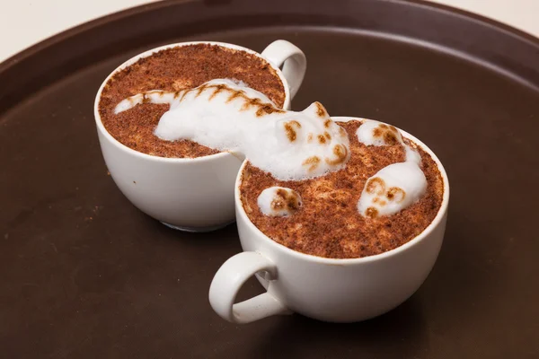 Coffee with foam in the form of a cat and a mouse on brown table