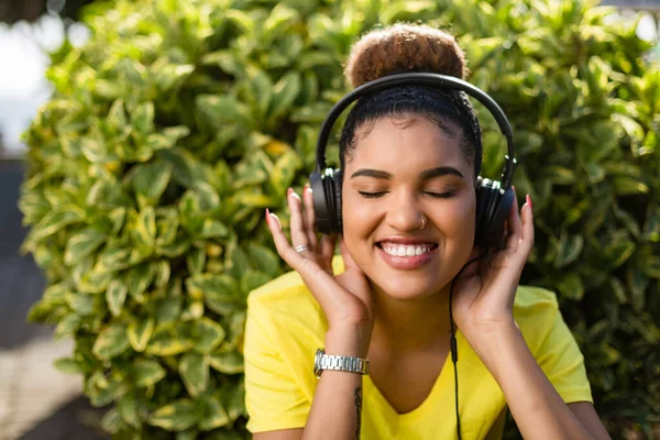 若い黒人アフリカ系アメリカ人の女性がヘッドフォンの屋外で音楽を聴く — ストック写真