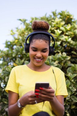 Güzel siyah Afrikalı Amerikalı kadın kulaklıkla müzik dinliyor.