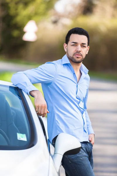 Jovem piloto latino-americano sentado ao lado de seu novo carro — Fotografia de Stock