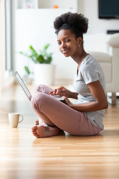 African American woman med en laptop i hennes vardagsrum - svart — Stockfoto