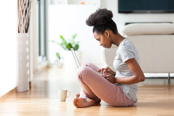 Afrikalı-Amerikalı kadın siyah onun oturma odasında - bir dizüstü bilgisayar kullanarak — Stok fotoğraf