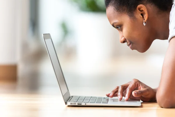Afrikai-amerikai nő használ egy laptop a nappaliban - fekete — Stock Fotó