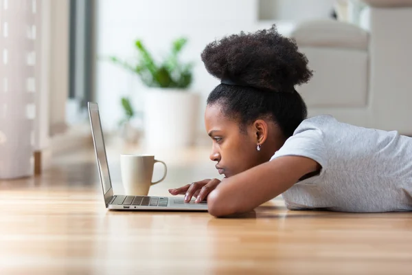 Mulher afro-americana usando um laptop em sua sala de estar - Preto — Fotografia de Stock