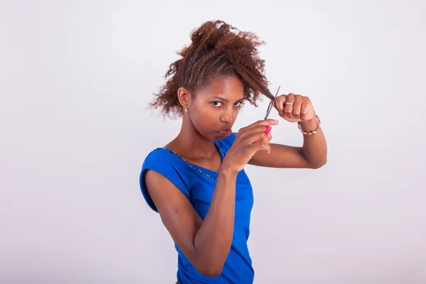 Giovane donna afro-americana tagliando i capelli afro crespi con s — Foto Stock