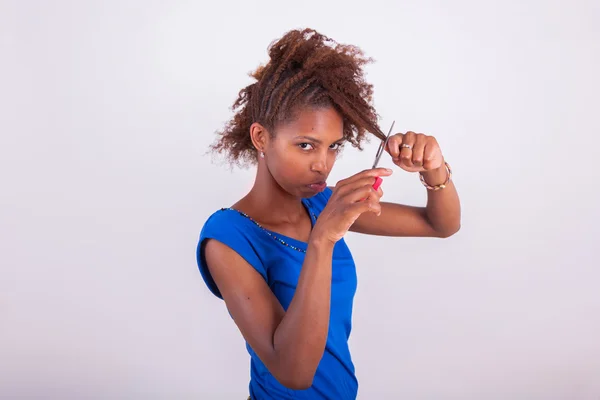 Joven mujer afroamericana cortando su pelo afro muy rizado con s — Foto de Stock