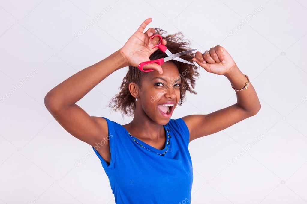 Young African American woman cutting her frizzy afro hair with s