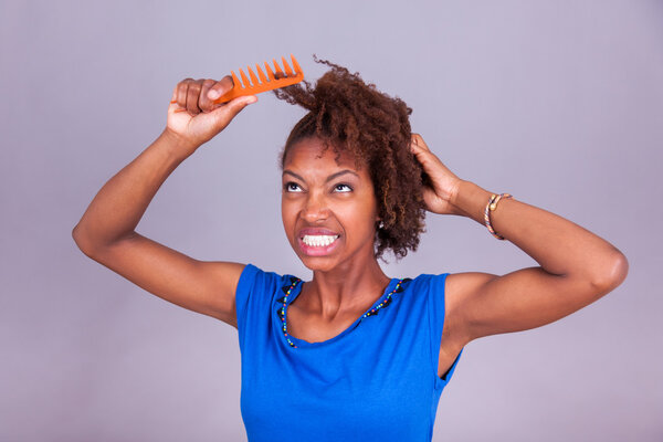 Young African American woman combing her frizzy afro hair - Blac