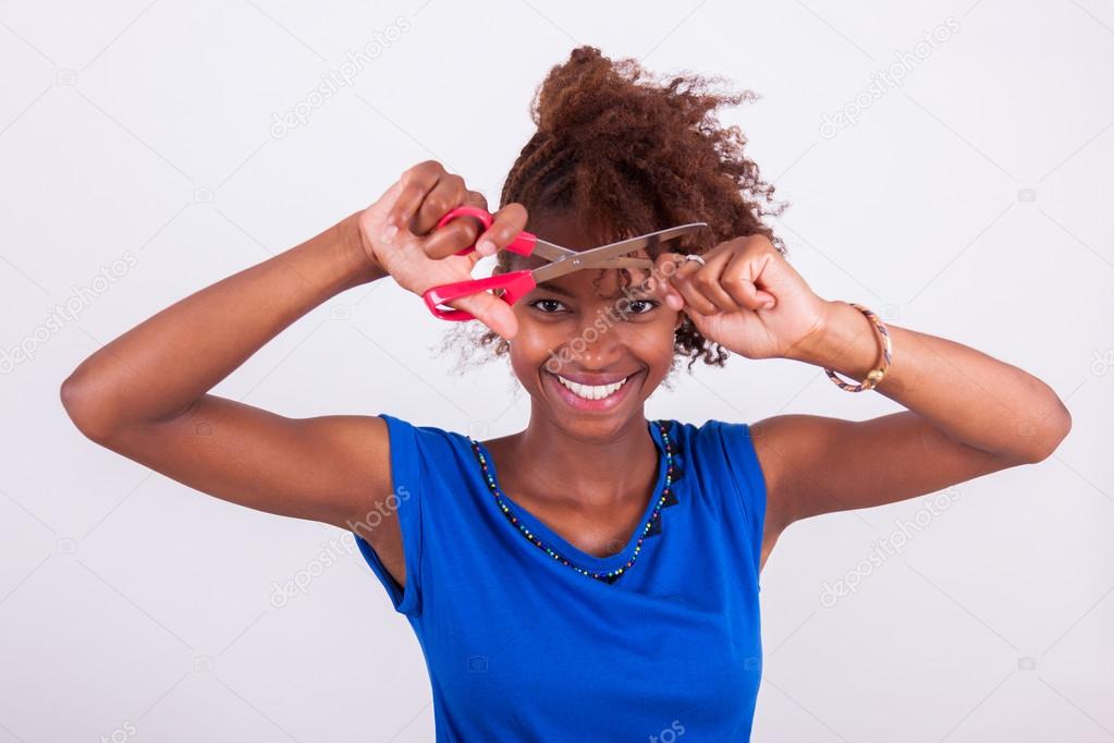 Young African American woman cutting her frizzy afro hair with s