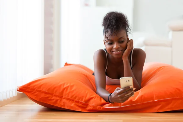 Mujer afroamericana enviando un mensaje de texto en un teléfono móvil —  Fotos de Stock