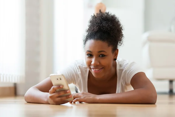 Αφρικανική αμερικανική γυναίκα που στέλνει ένα μήνυμα κειμένου σε ένα κινητό τηλέφωνο — Φωτογραφία Αρχείου