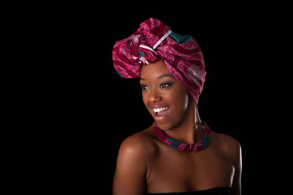 Young beautiful african woman wearing a traditional headscarf, Isolated over black background