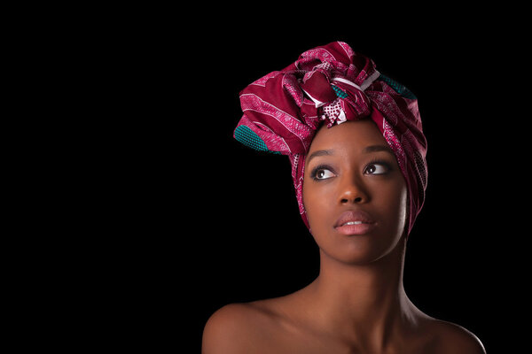 Young beautiful african woman wearing a traditional headscarf, Isolated over black background