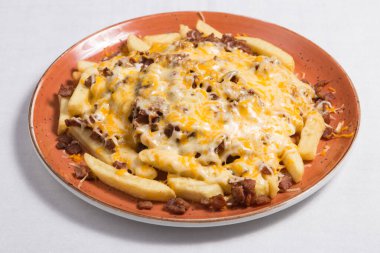 Beyaz arka planda pastırmalı ve peynirli patates kızartması.