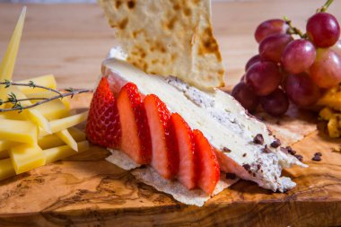 Çeşitli peynir dilimleri, ahşap kesim tahtasında peynir karışımı. Şarap çerezi. Camembert peyniri, parmesan peyniri.