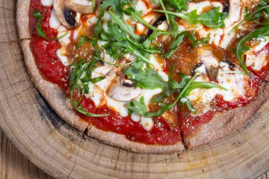 Sağlıklı sebzeler ve mantarlar ahşap arka planda vejetaryen pizza.