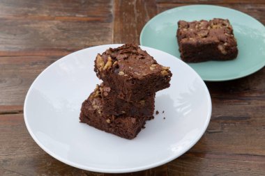 Çikolatalı Brownie beyaz bir tabakta servis edildi. Ahşap arkaplan