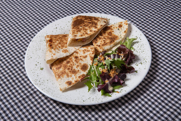 Mexican quesadilla with salad on a white plate