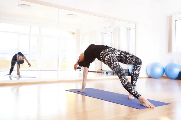 Mujer haciendo yoga en una alfombra de ejercicio —  Fotos de Stock