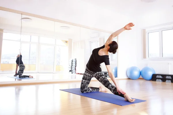 Mulher fazendo ioga em um tapete de exercício — Fotografia de Stock