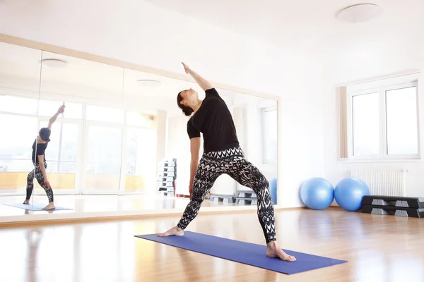 Mujer haciendo yoga en una alfombra de ejercicio —  Fotos de Stock