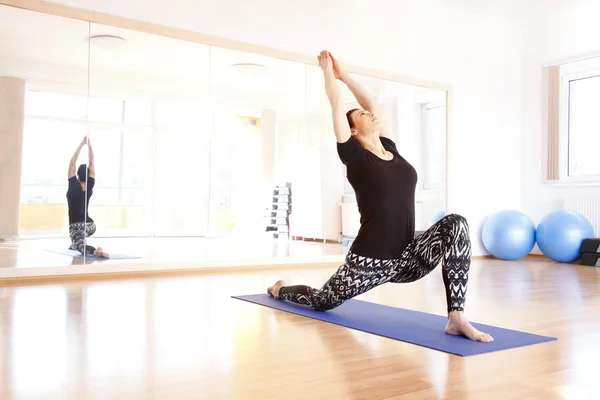 Kvinnan gör yoga på en träningsmatta — Stockfoto